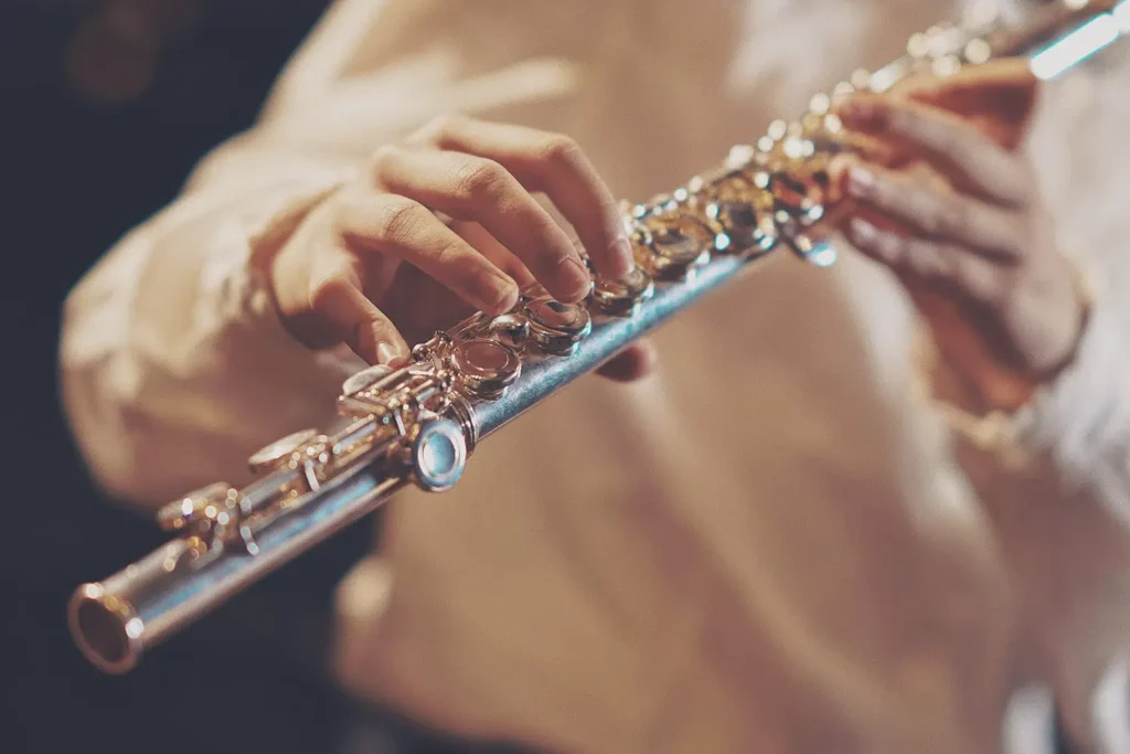 Photo of a close up of a person playing a flute. Polyrhythm article.