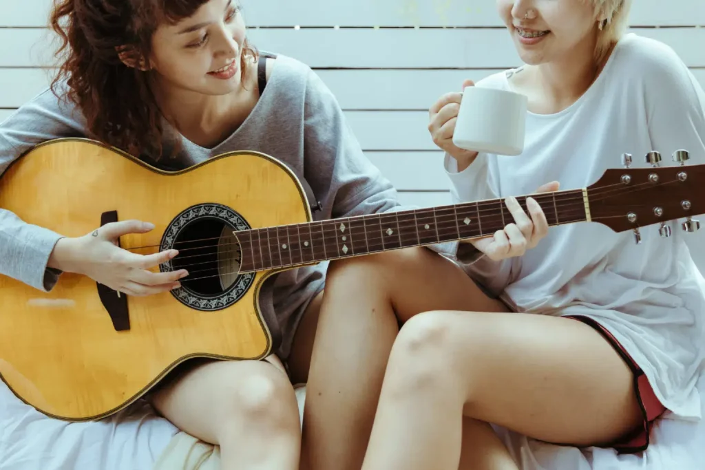 Photo of two people, left with a guitar, right with a mug