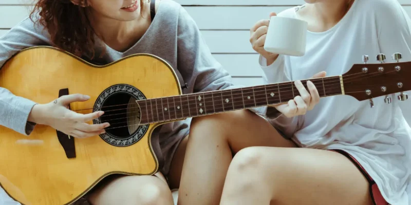 Photo of two people, left with a guitar, right with a mug