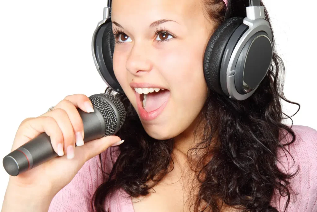 Photo of a person wearing studio headphones, singing in a microphone, white background