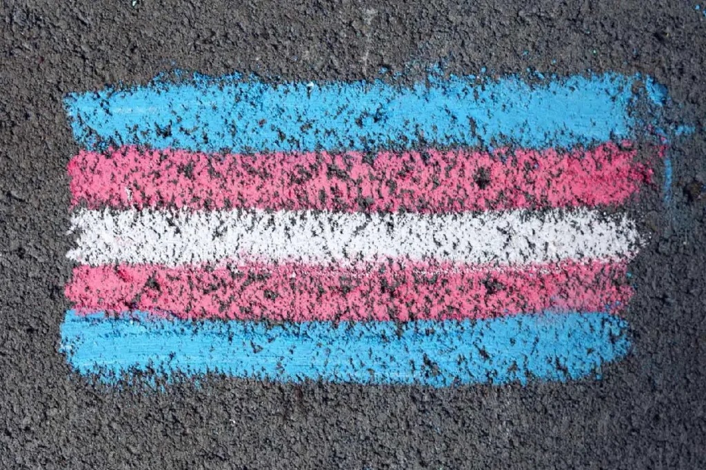 Trans pride flag on road draw with chalk. Gender dysphoria article.