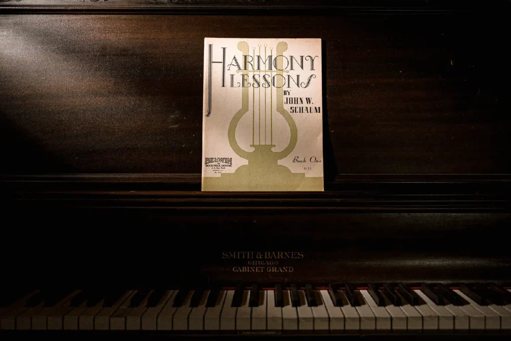 Photo of a piano with "Harmony Lessons, Book One" by John W. Schaum on the music stand
