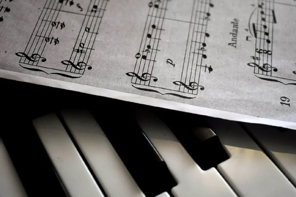 Closeup photo of piano keys with a sheet of a music score over it