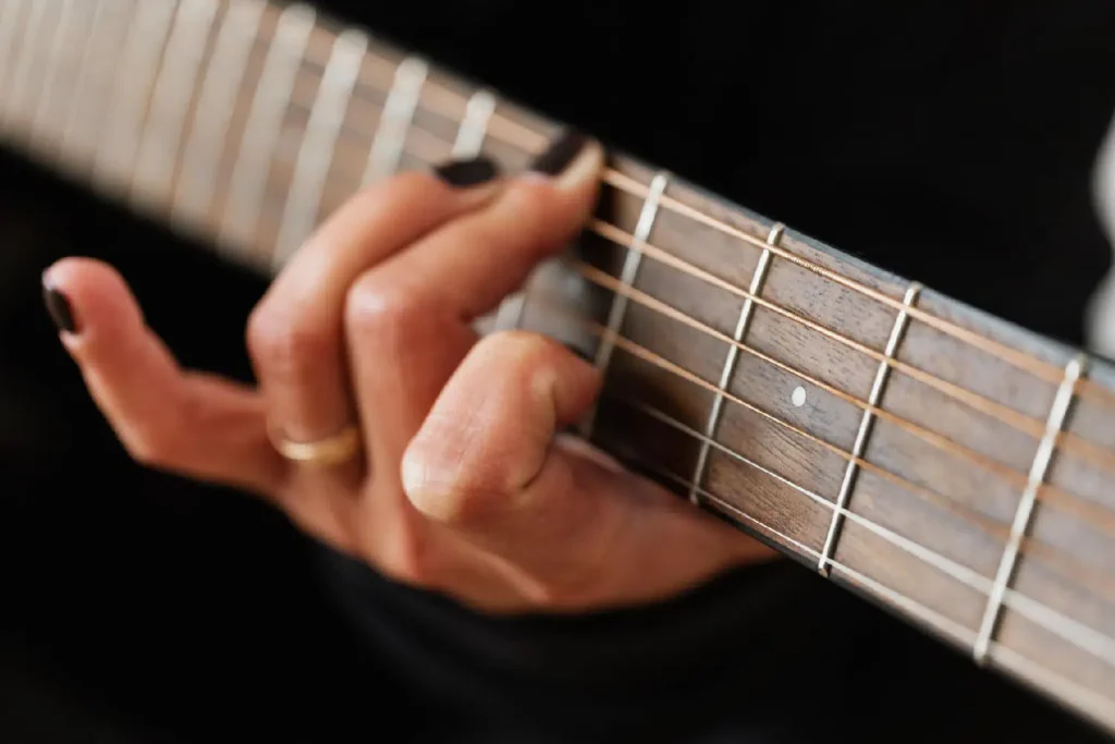 Closeup photo of a person's hand on the neck of a guitar
