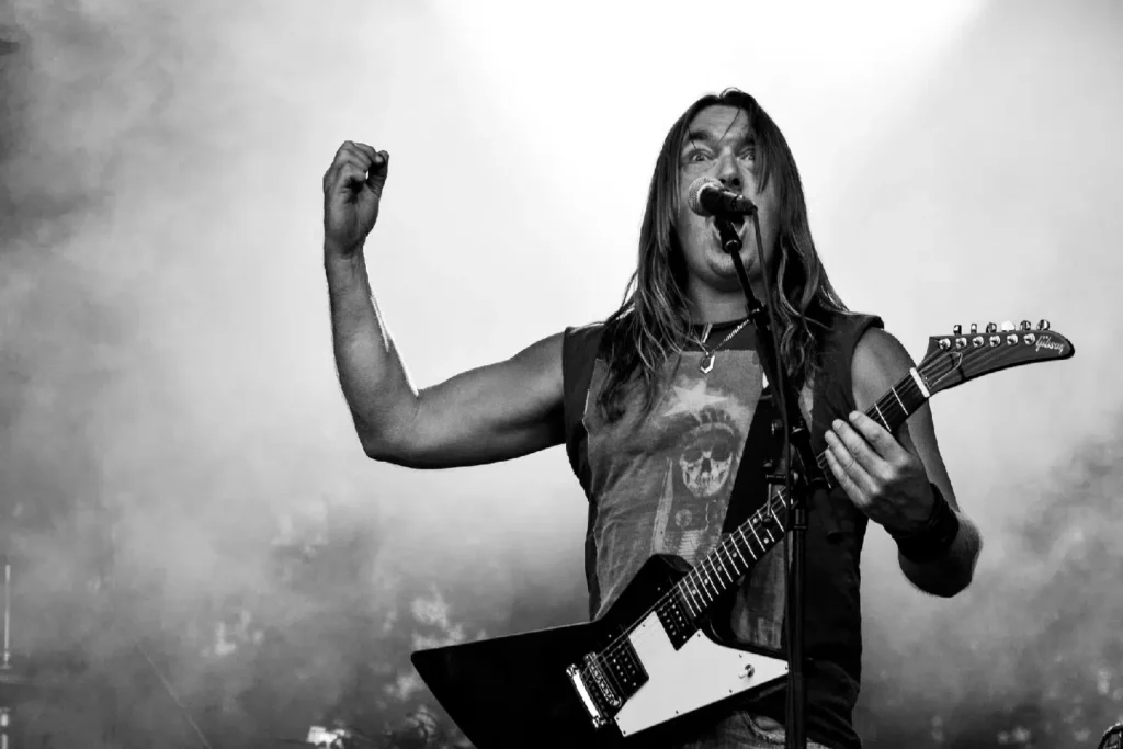 Black and white photo of a man with an electric guitar singing into a microphone