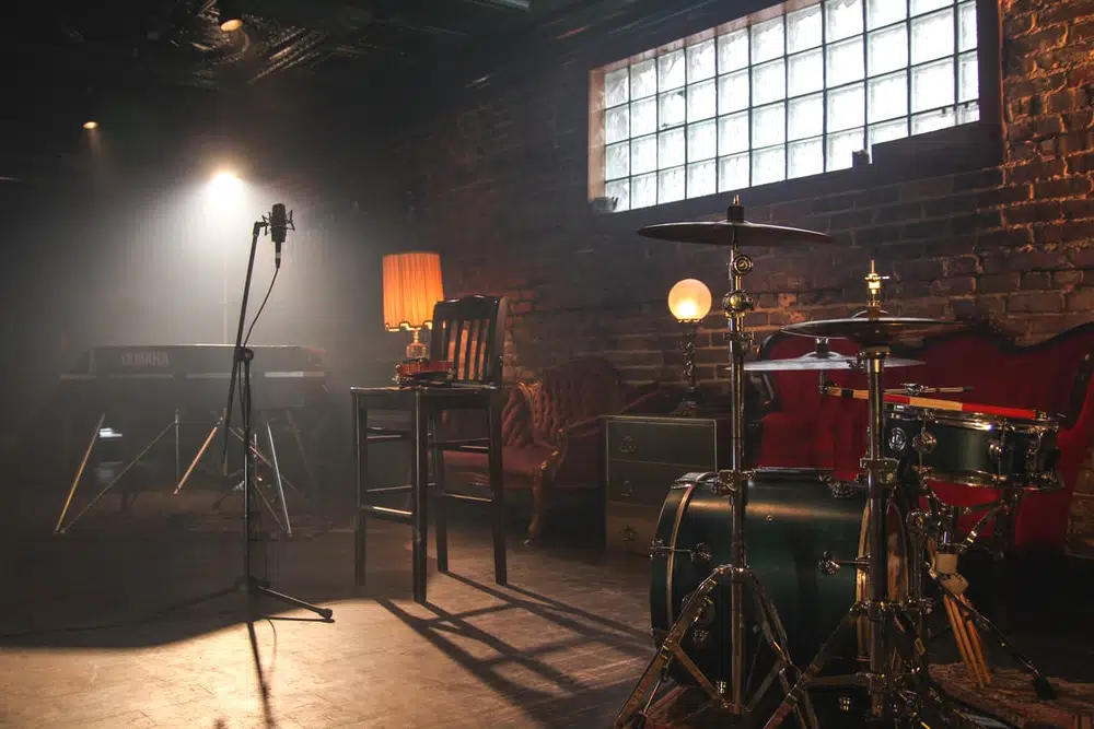 Photo of a stage set up with a drum set, microphone, and couches