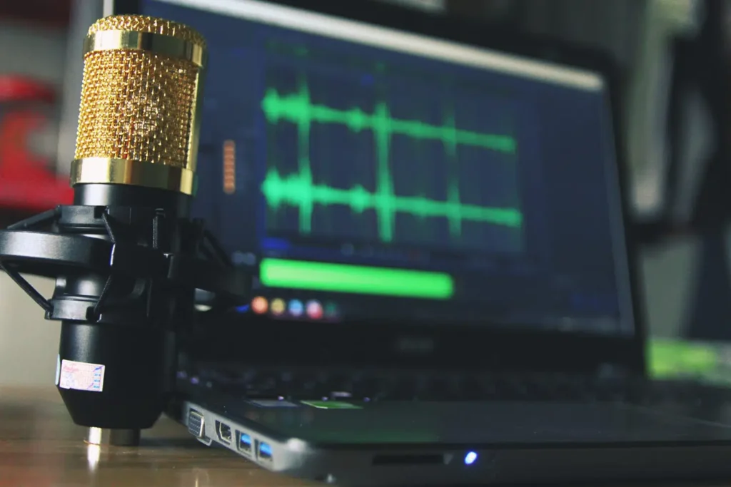 Photo of a microphone in a recording studio, a laptop in the background with an audio production program on the screen. Diaphragmatic breathing.