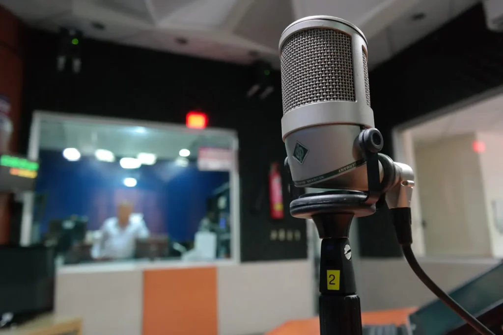 Photo of a microphone in a recording studio, with a blurry background. Gender affirming vocal coaching lessons.